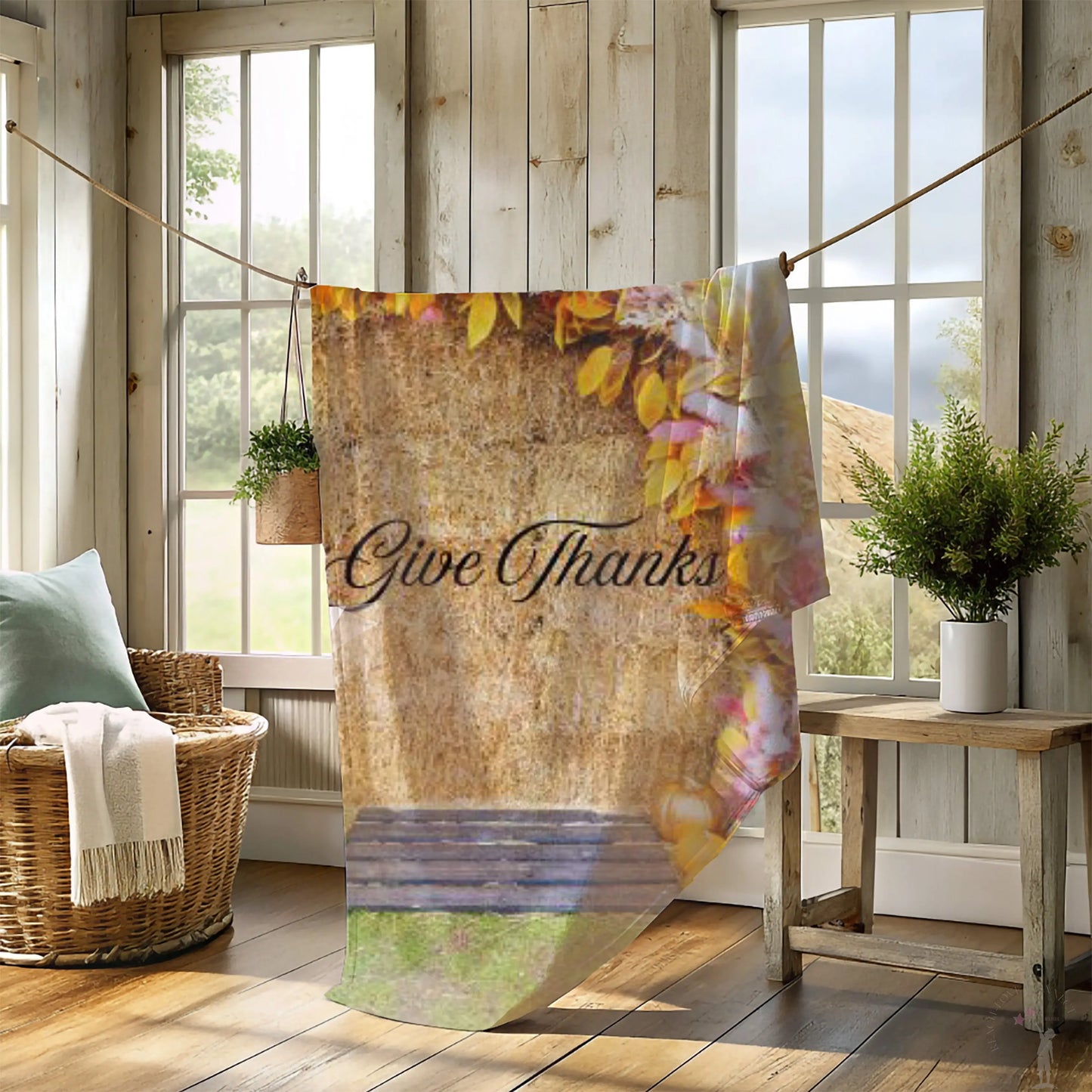 Decorative blanket with 'Give Thanks' text in a rustic room with windows and plants.
