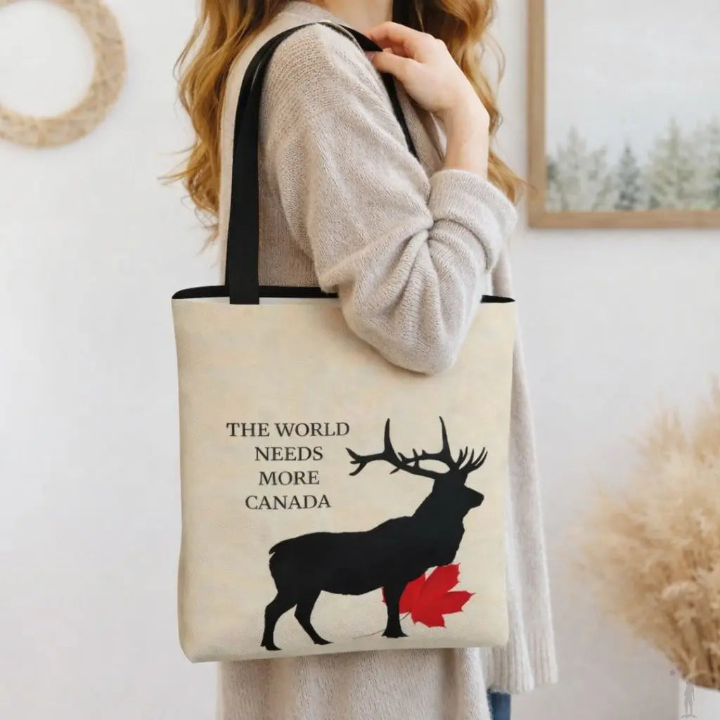 Person holding a tote bag with a deer and leaf design and text 'The World Needs More Canada'.