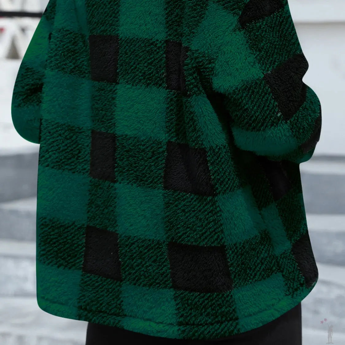 Green and black checkered coat worn by a person, with a blurred indoor background.