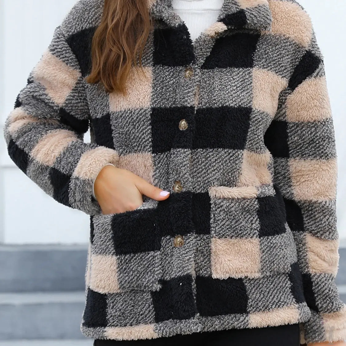 Person wearing a checkered tan and black button up coat with a blurred background