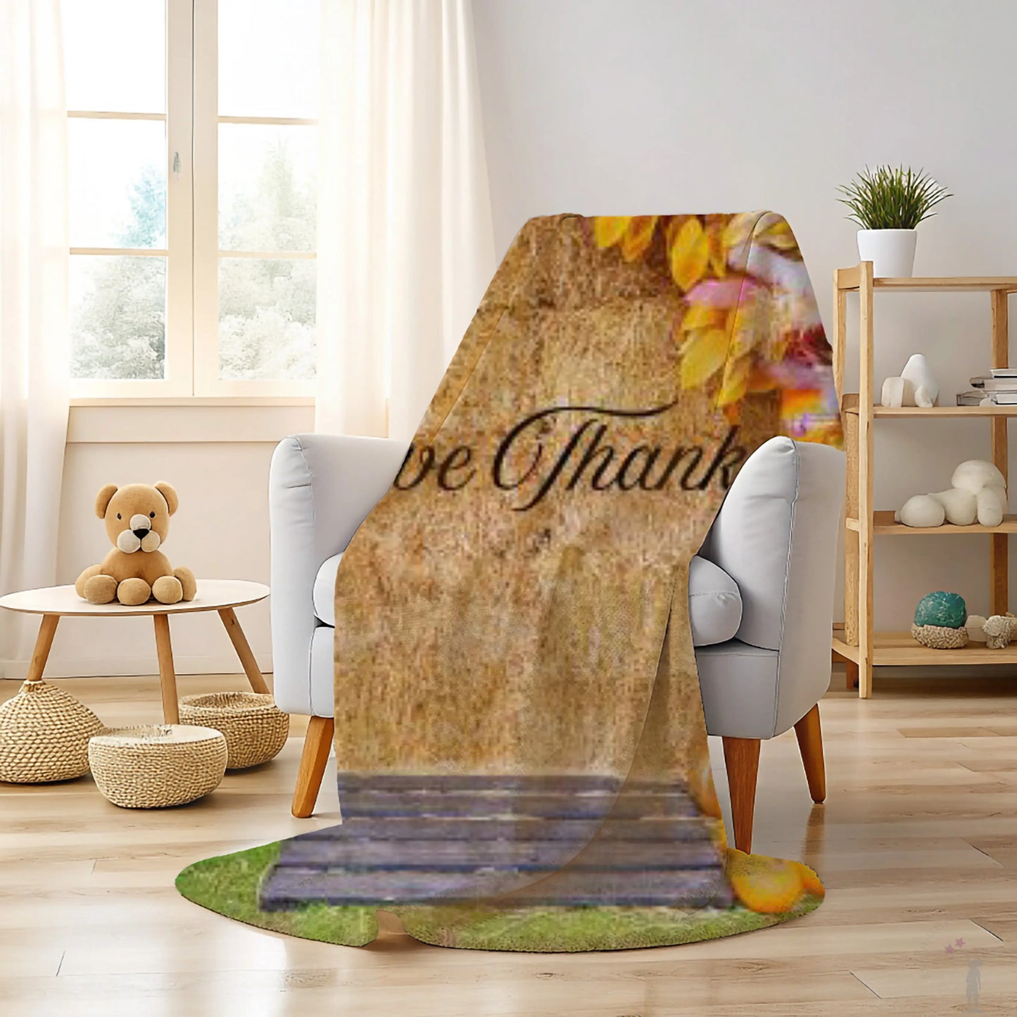Floral-themed blanket with 'Be Thankful' text draped over a chair in a cozy living room.