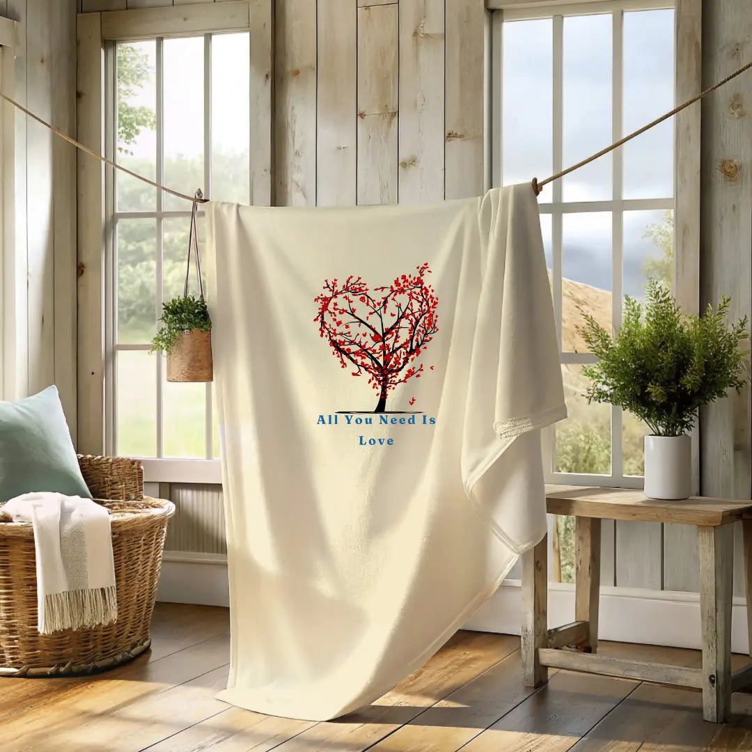 Romantic beige blanket featuring a tree with red heart branches and the phrase “All You Need Is Love.” Limited Edition Valentine’s Day blanket – Reach Love Connect Boutique